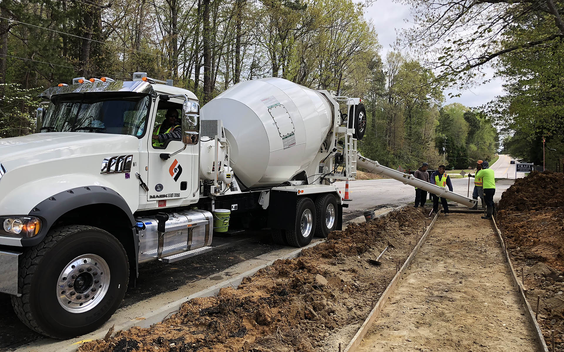 An L&L Concrete mixer truck delivers ready-mixed concrete to a crew of L&L Concrete workers building a concrete sidewalk near Raleigh, NC.
