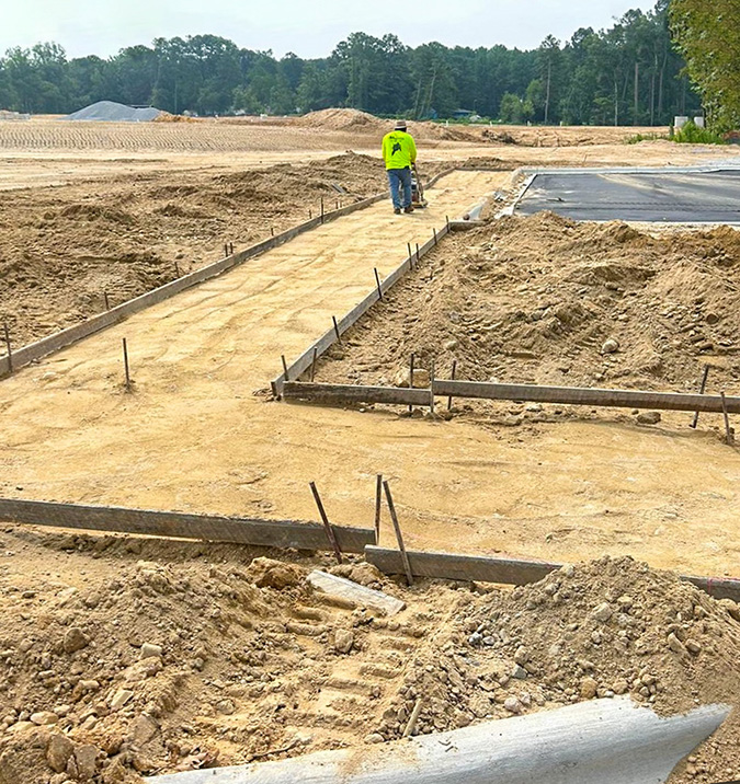 L&L Concrete worker prepares the soil inside newly-constructed concrete forms.
