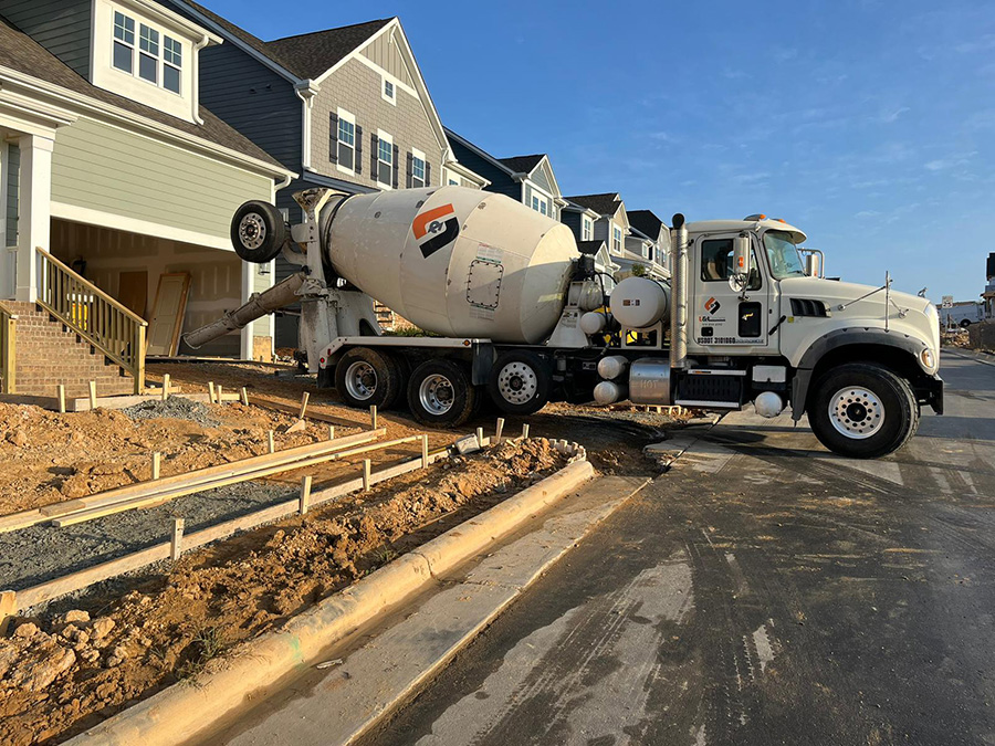 A concrete mixer truck prepares to deliver fresh ready-mixed concrete into construction forms for a new concrete driveway.